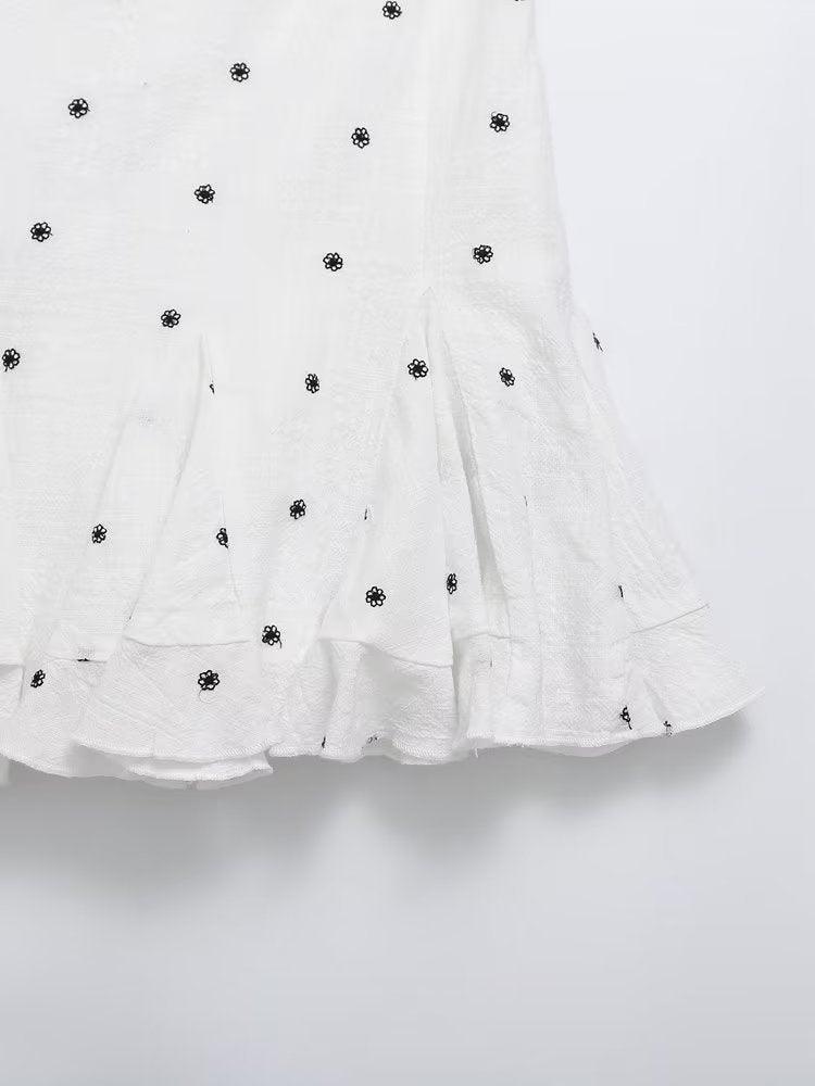 Floral pattern embroidered skirt in white polyester fabric with black floral motifs, A-line short style for casual summer wear.