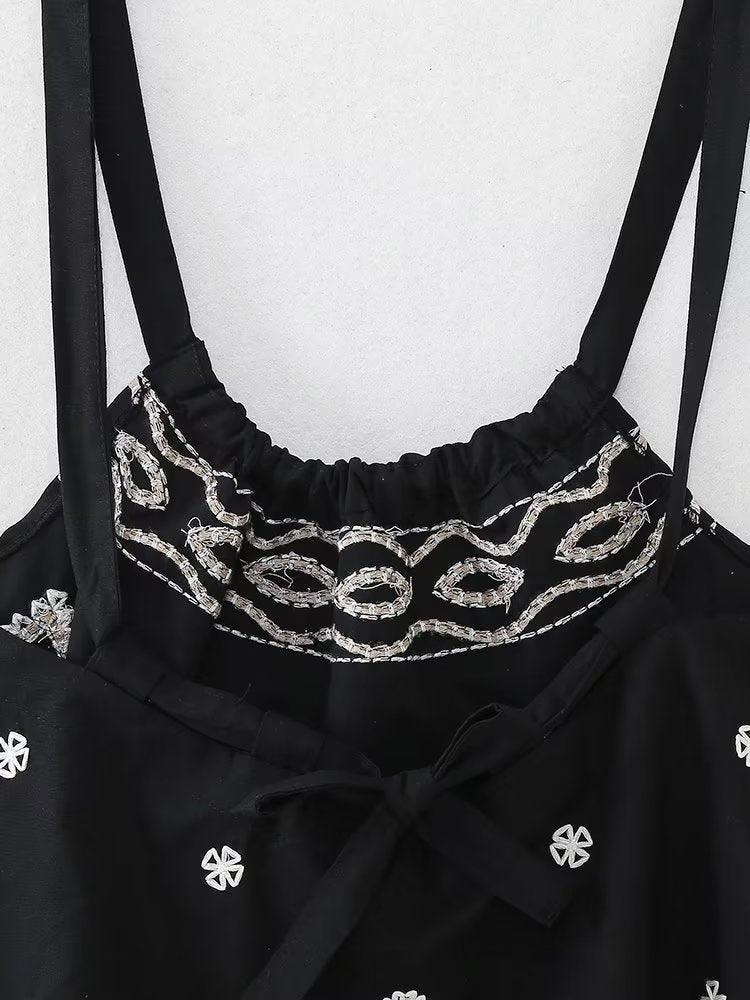 Spaghetti strap embroidered black top with bow and boho design.
