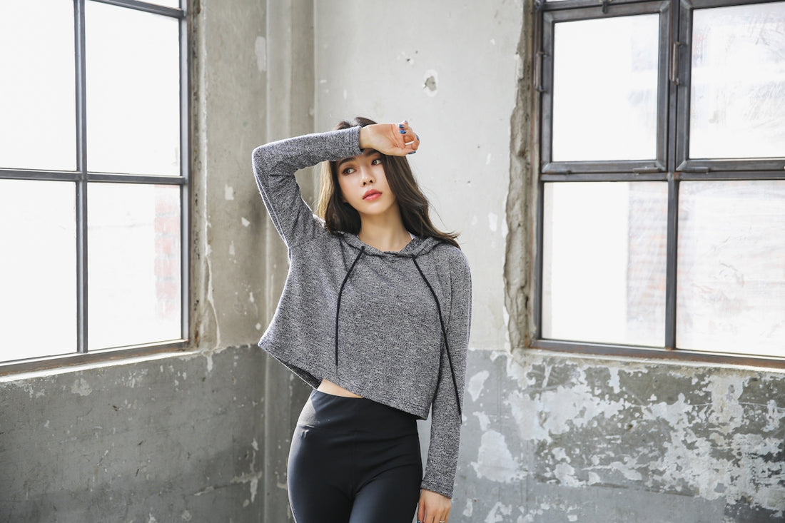 woman in gray sweater and black pants standing by the window