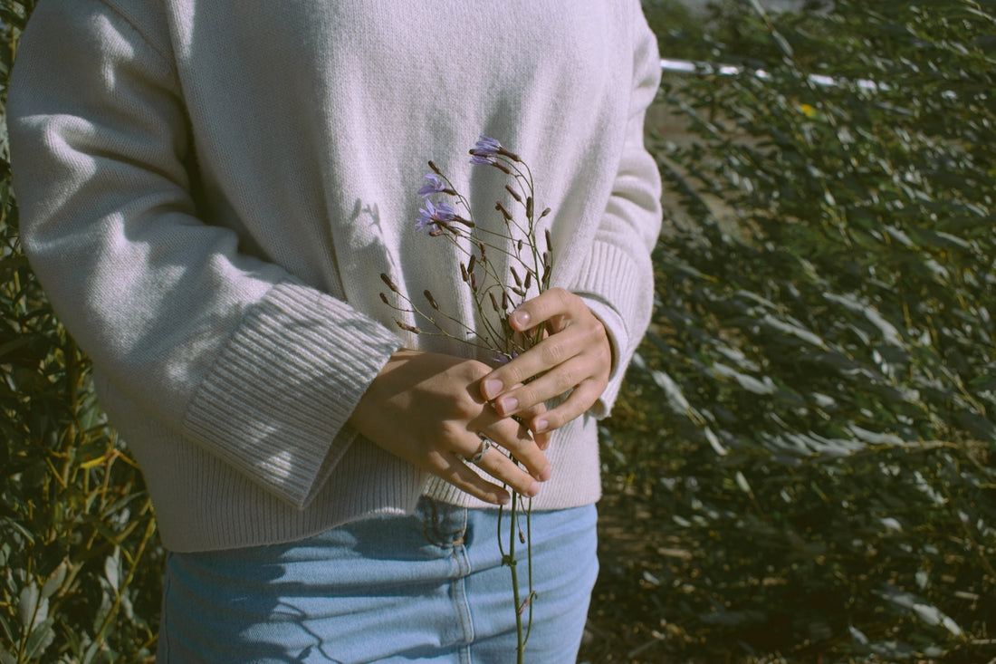 person in white sweater and blue denim jeans