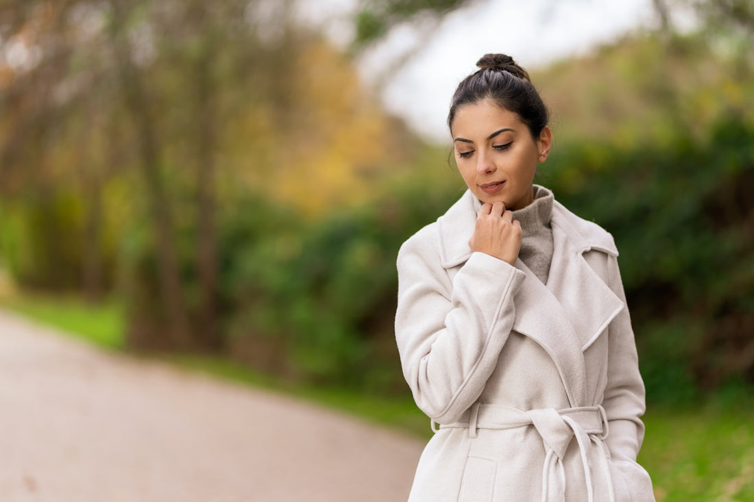 a woman in a white coat standing on a road