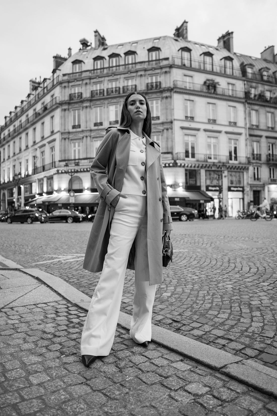A woman standing on a street corner in front of a building