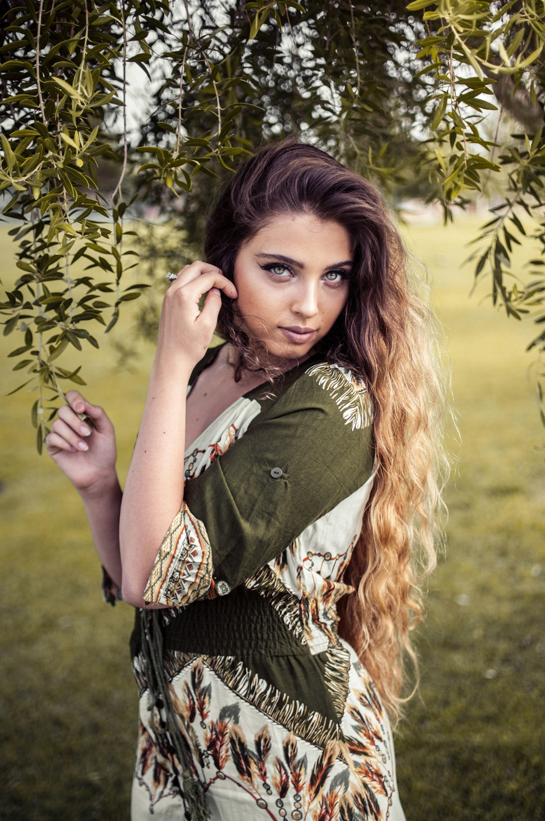 A woman poses elegantly outdoors with soft lighting.
