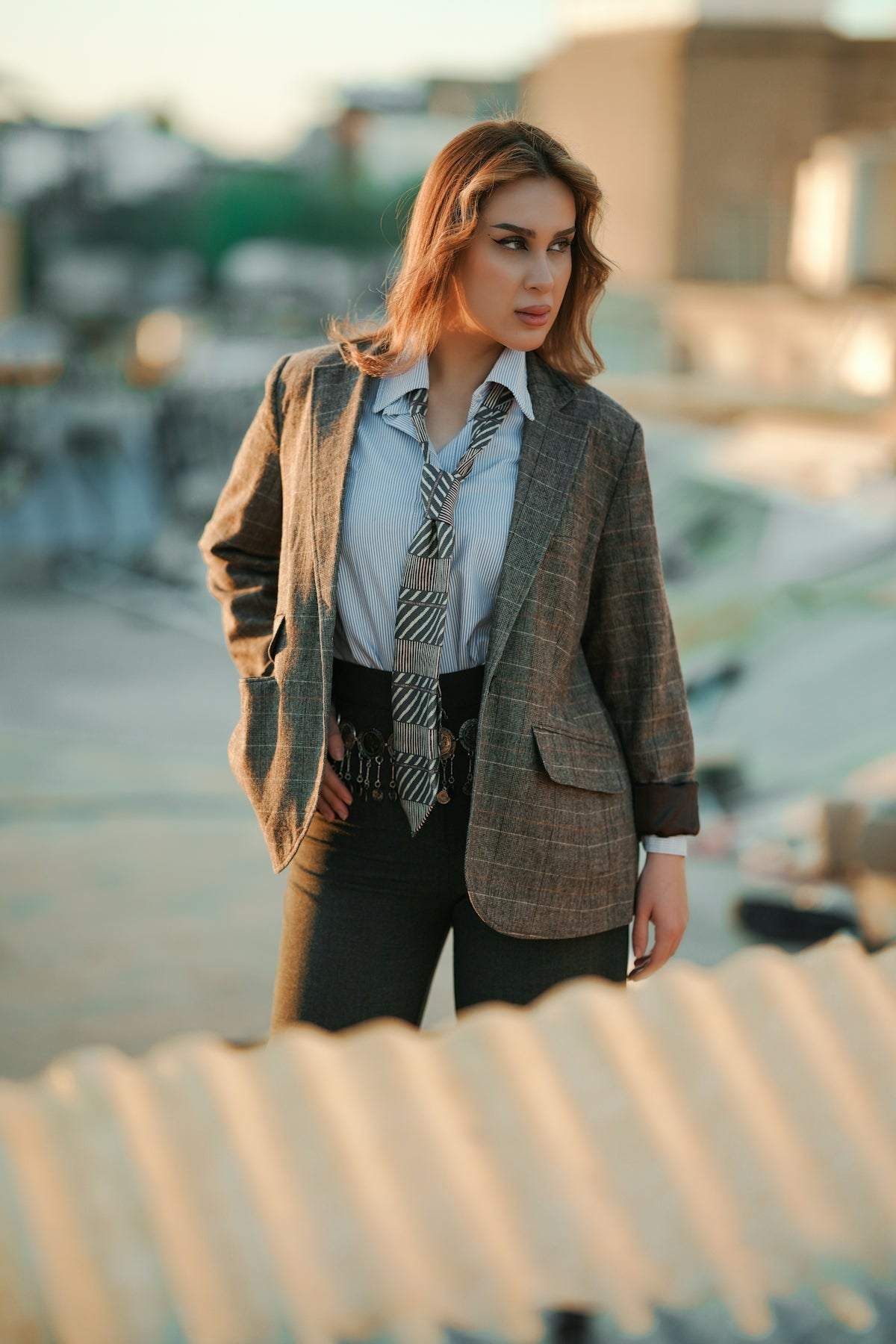 Woman in blazer and tie standing outdoors.