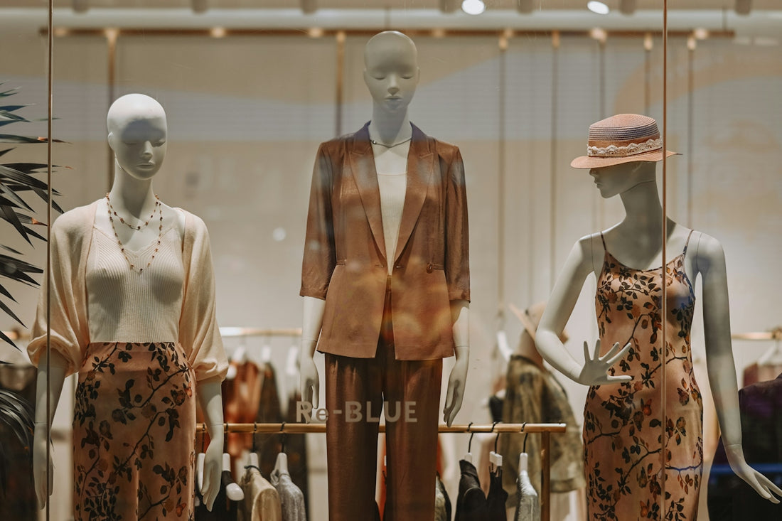 Three mannequins display fashionable clothing in a store window