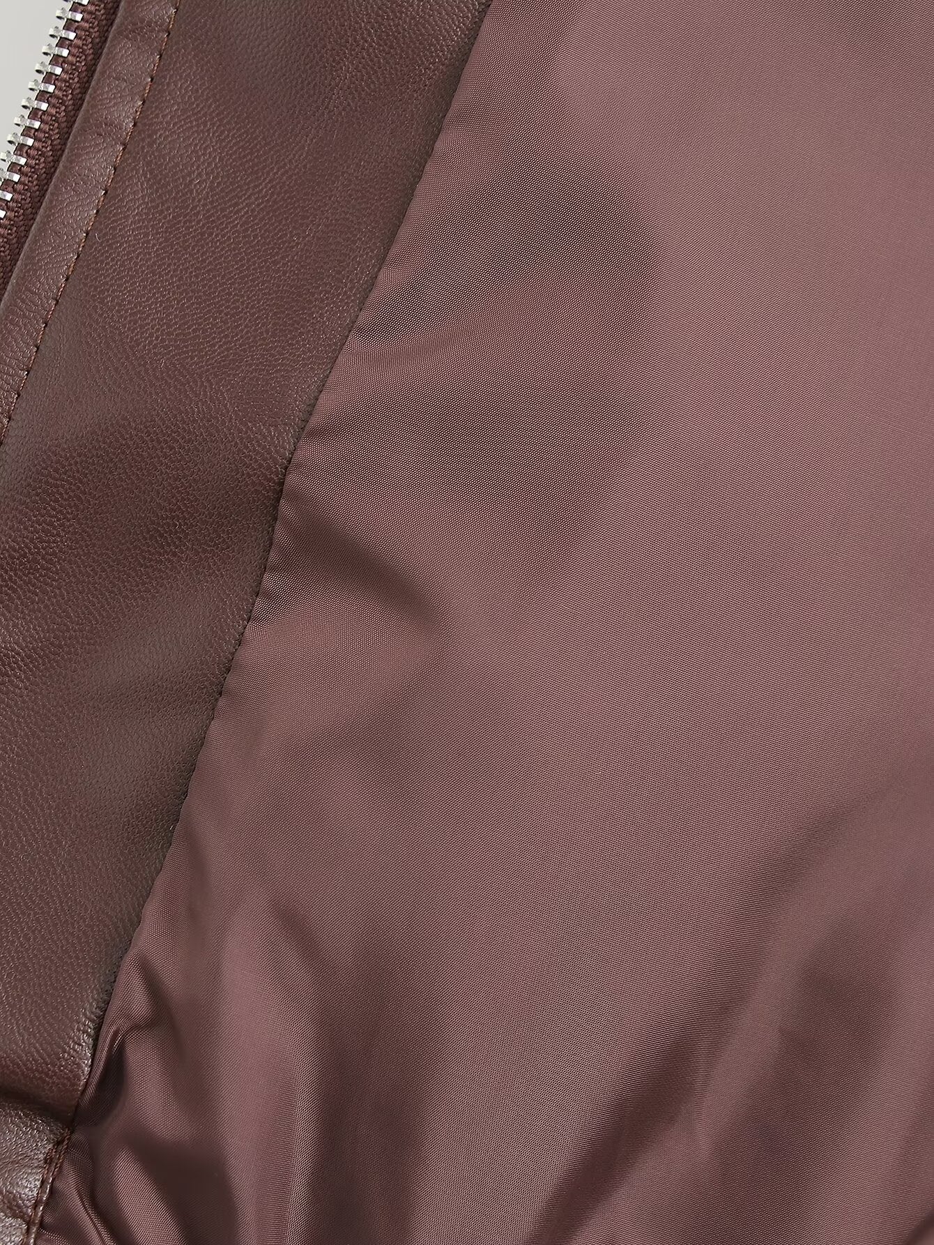Close-up of a brown nylon jacket showing the smooth fabric texture, a seam, and a zipper detail.