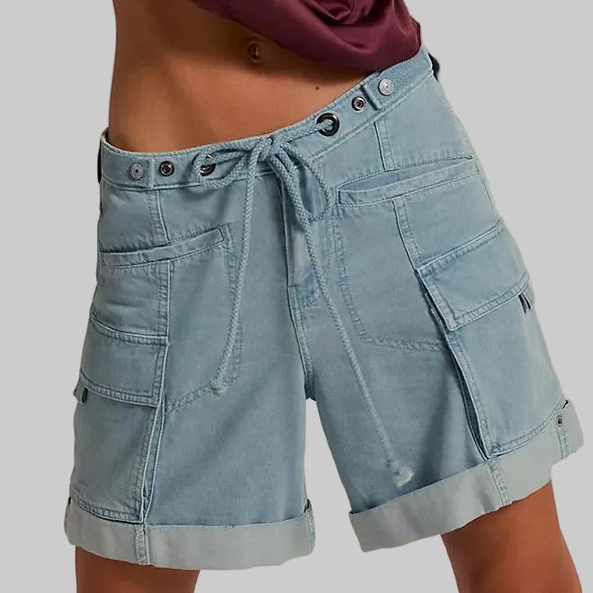 Light blue denim shorts with a tie waist on a beige background