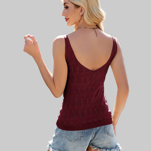 Woman wearing a burgundy sleeveless top with a white building in the background