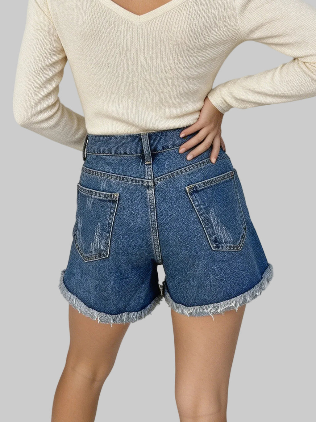Person wearing blue denim shorts with a plain background