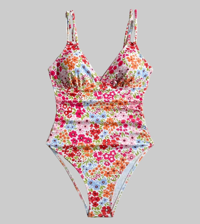 Floral one-piece swimsuit on a white background with flowers and a straw hat.