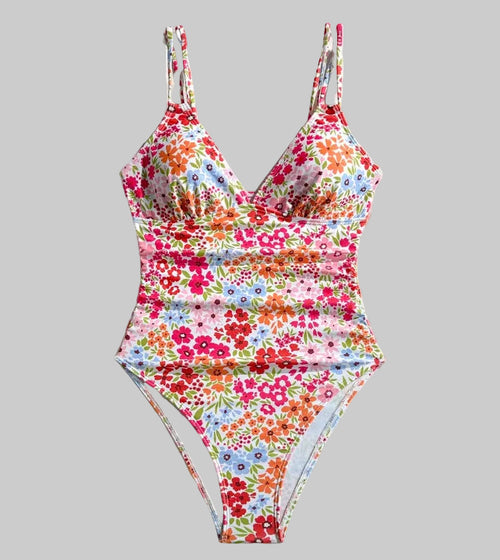Floral one-piece swimsuit on a white background with flowers and a straw hat.