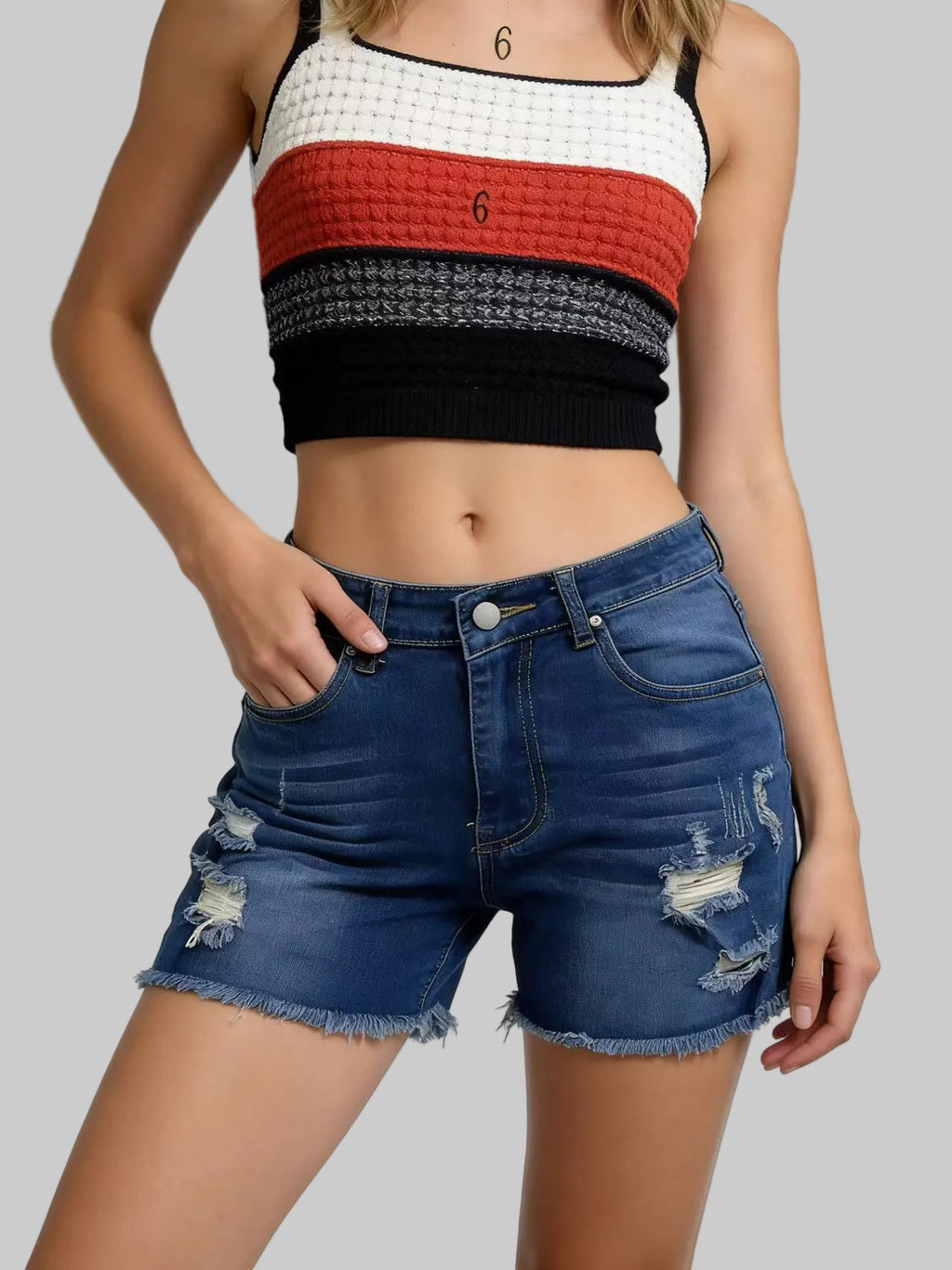 Person wearing a colorful cropped top and blue denim shorts on a gradient background