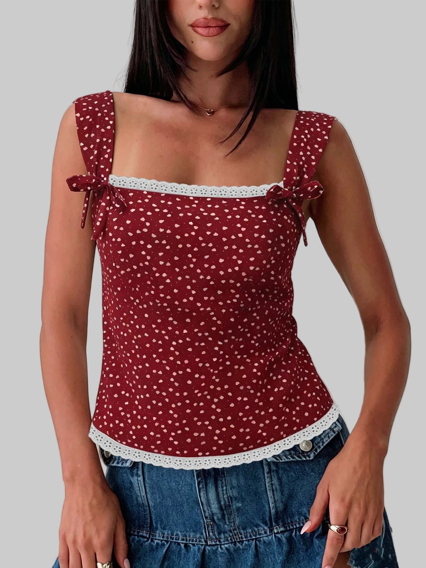 Woman wearing a red polka dot top with lace trim against a white background