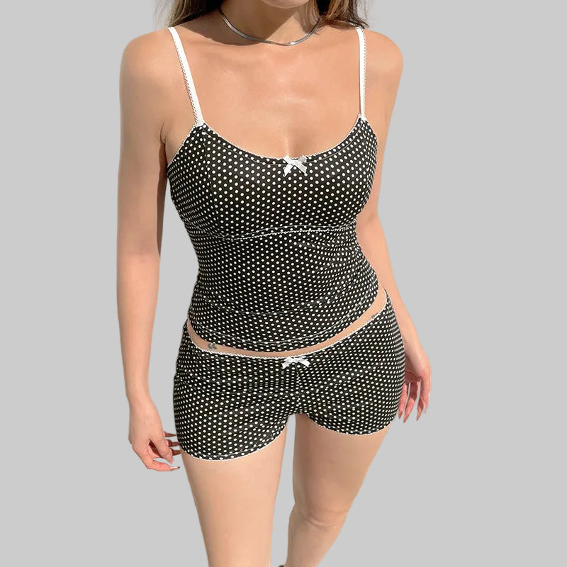 Person wearing a black and white polka dot swimsuit against a light gray wall.