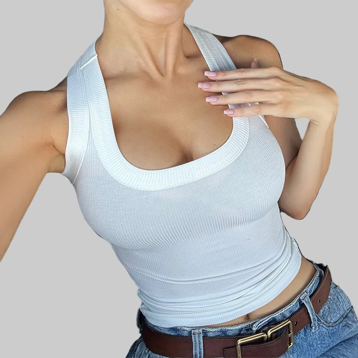 Person wearing a white tank top and blue jeans sitting in a car.