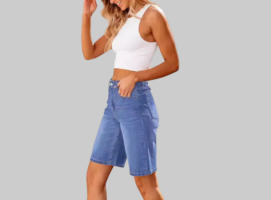 Woman wearing a white tank top and blue denim shorts on a white background