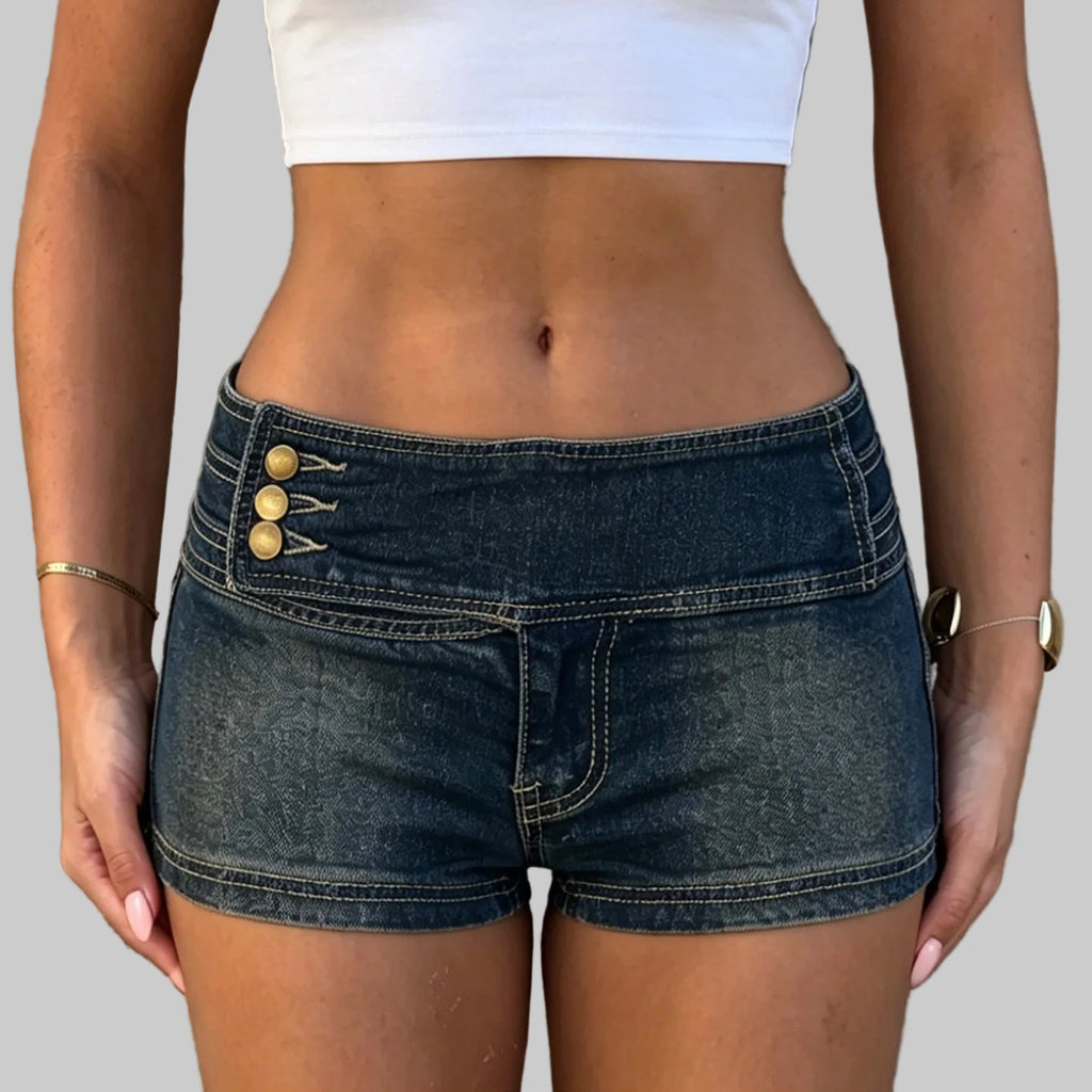 Person wearing blue denim shorts with gold buttons against a stone wall background
