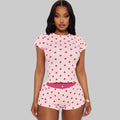 Woman wearing a pink pajama set with heart patterns on a white background