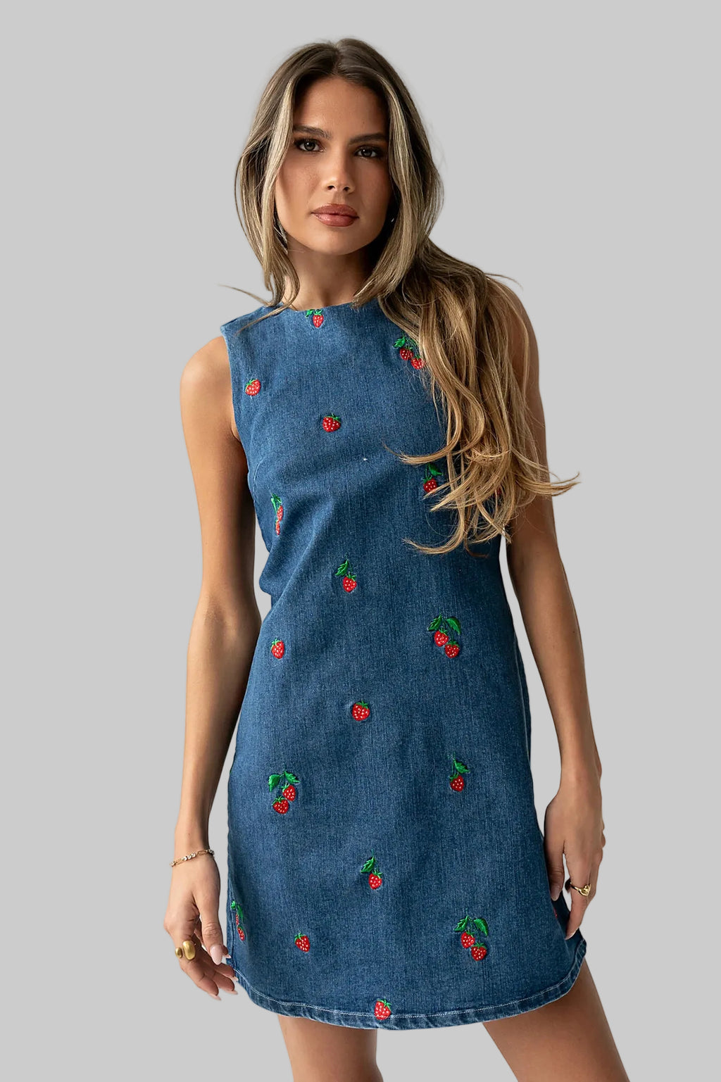 Woman wearing a blue dress with cherry patterns on a white background