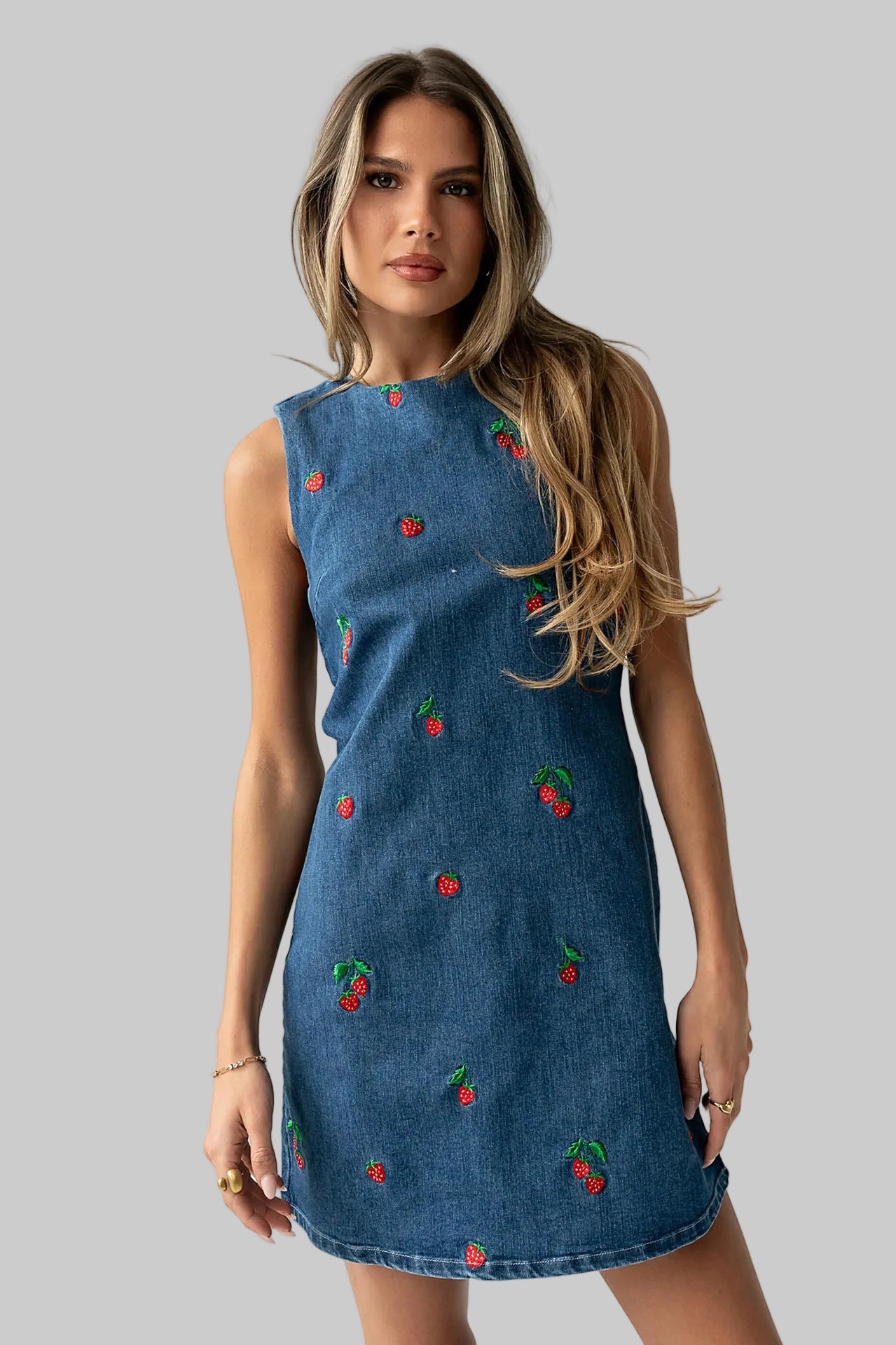 Woman wearing a blue dress with cherry patterns on a white background