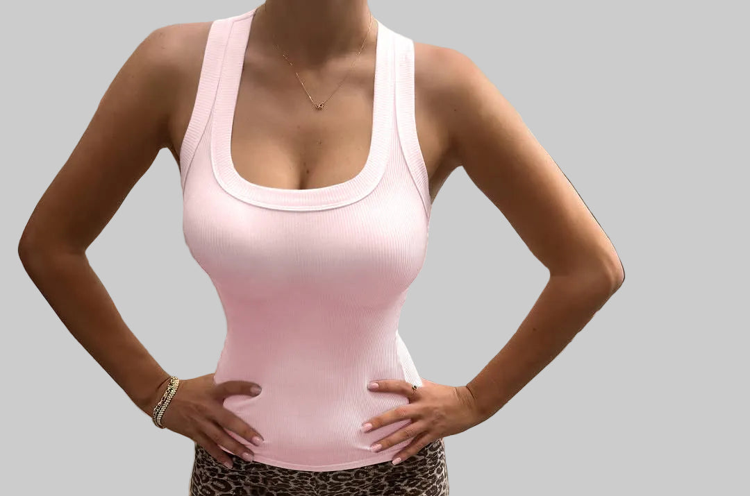 Person wearing a pink tank top and leopard print shorts standing on a concrete path.