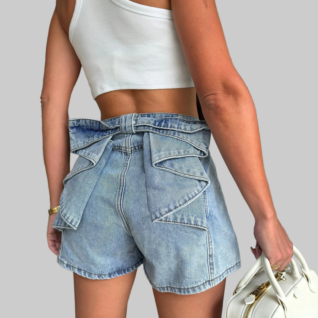 Person wearing a white crop top and blue denim shorts in an indoor setting.