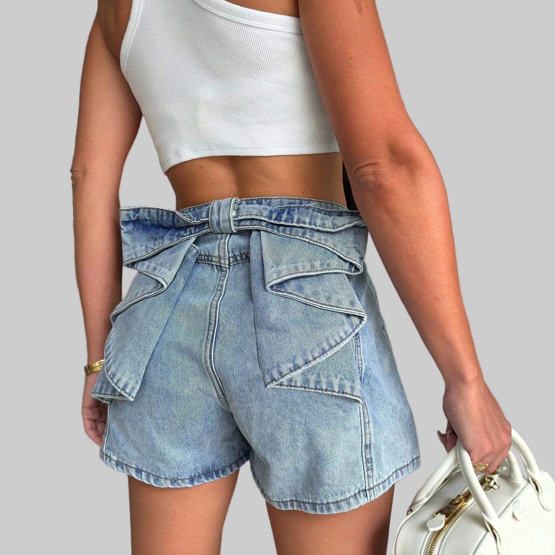 Person wearing a white crop top and blue denim shorts in an indoor setting.