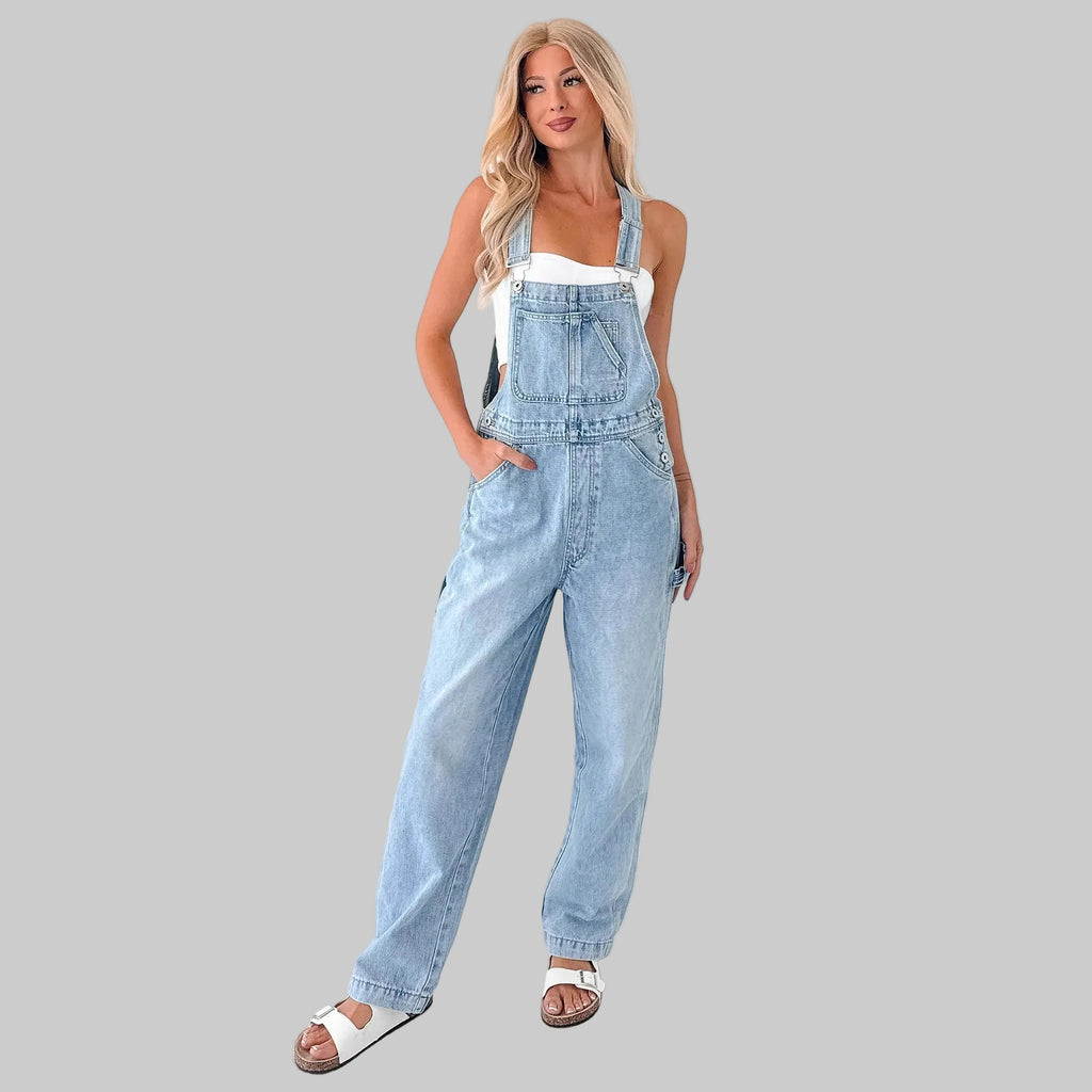 Woman wearing light blue denim overalls against a white background