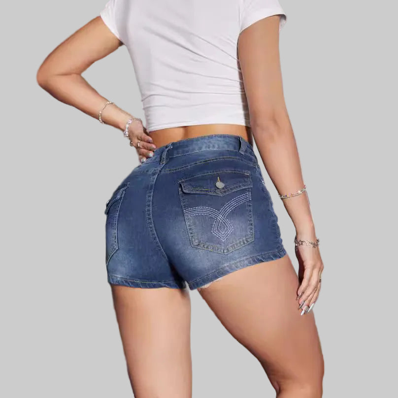 Person wearing blue denim shorts and a white crop top against a neutral background