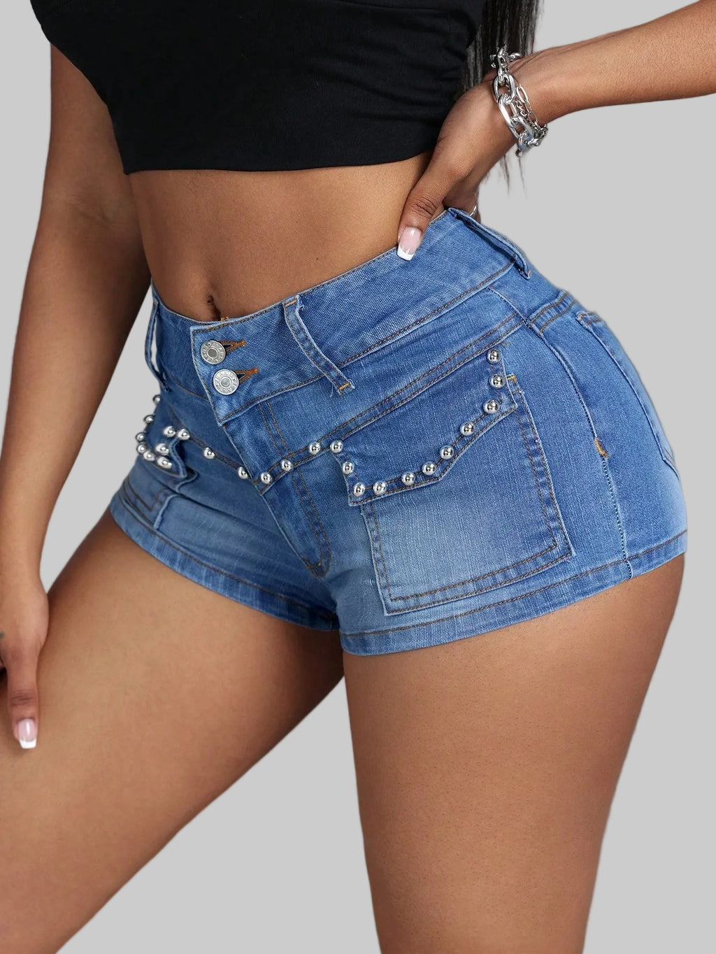 Blue denim shorts with embellishments on a plain background