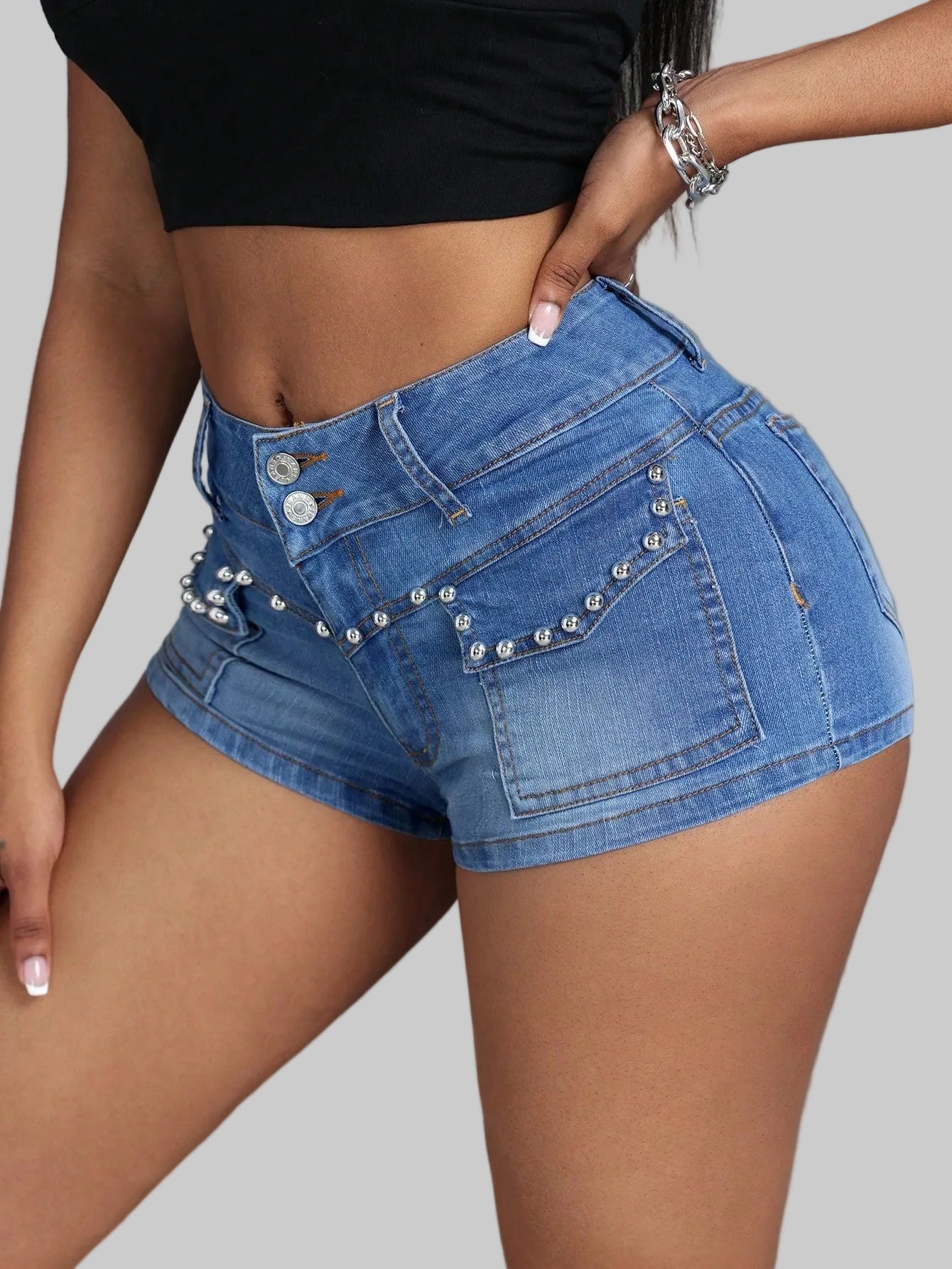Blue denim shorts with embellishments on a plain background