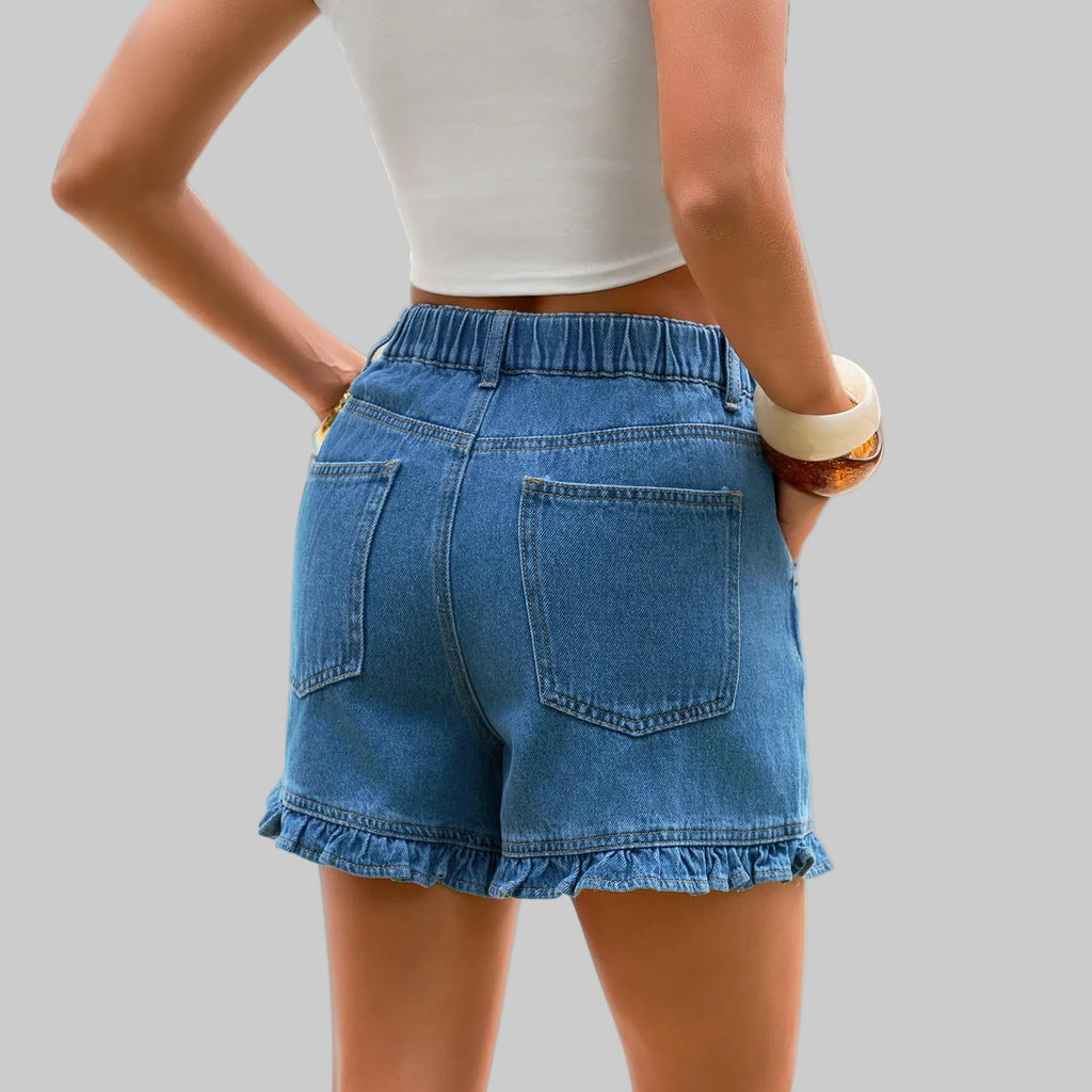 Person wearing blue denim shorts by a poolside