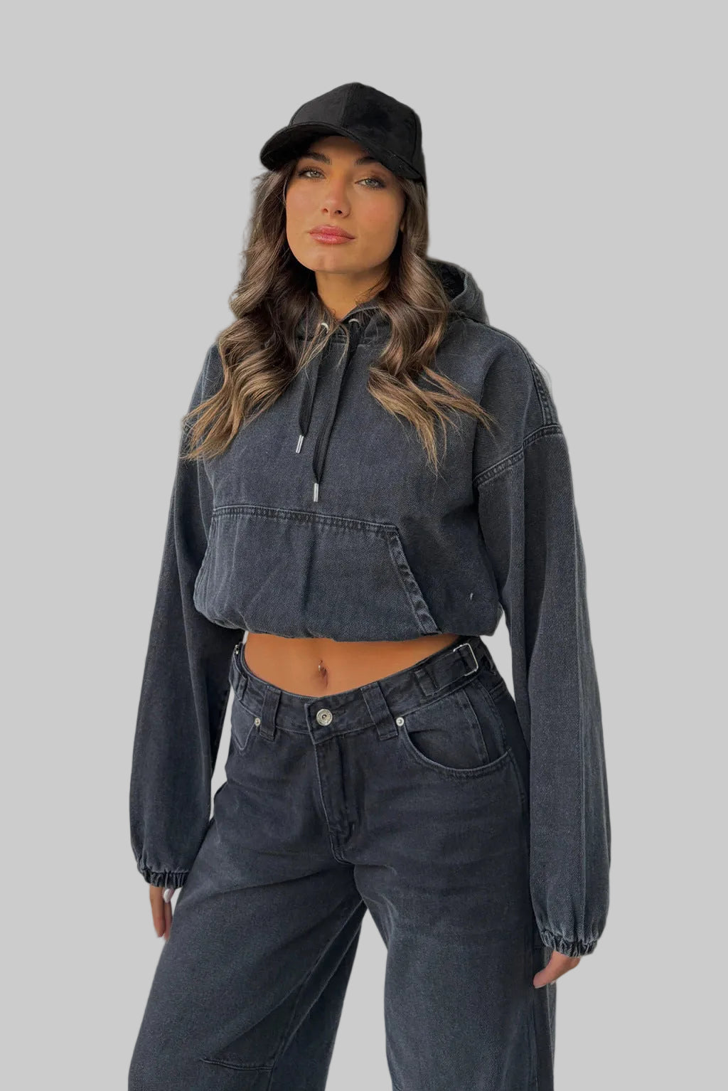 Woman wearing a dark denim jacket and pants standing outdoors.