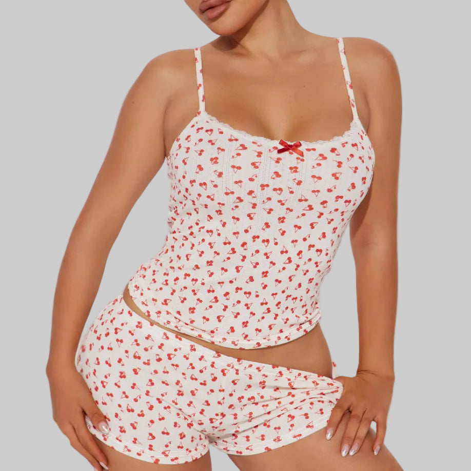 Woman wearing a white top and shorts with red floral pattern on a plain background
