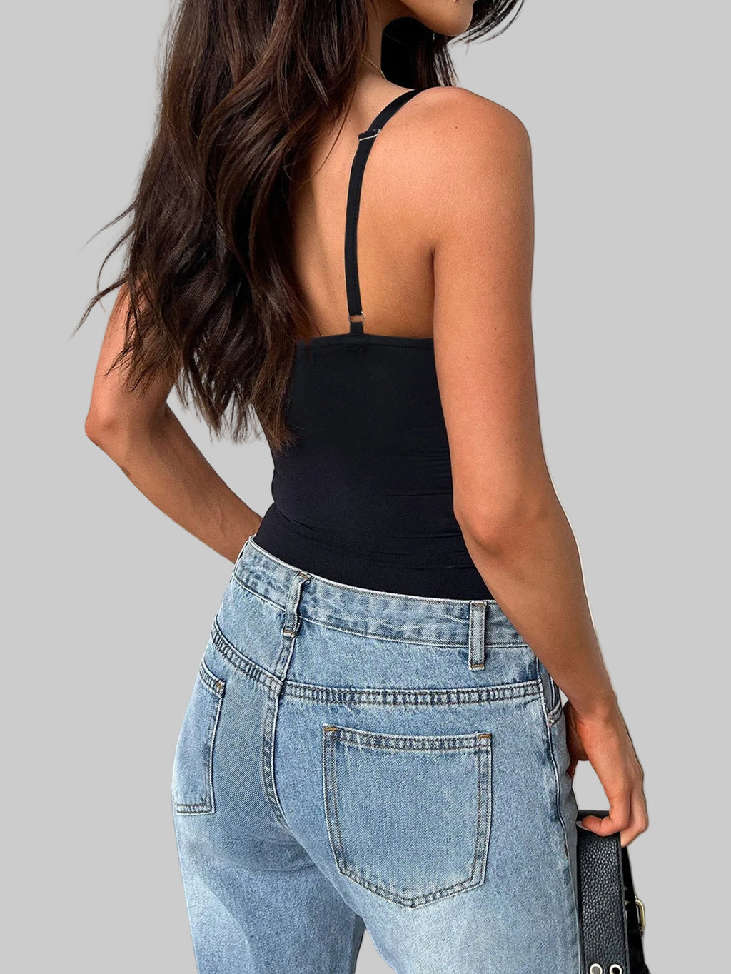 Person wearing a black top and blue jeans in an indoor setting