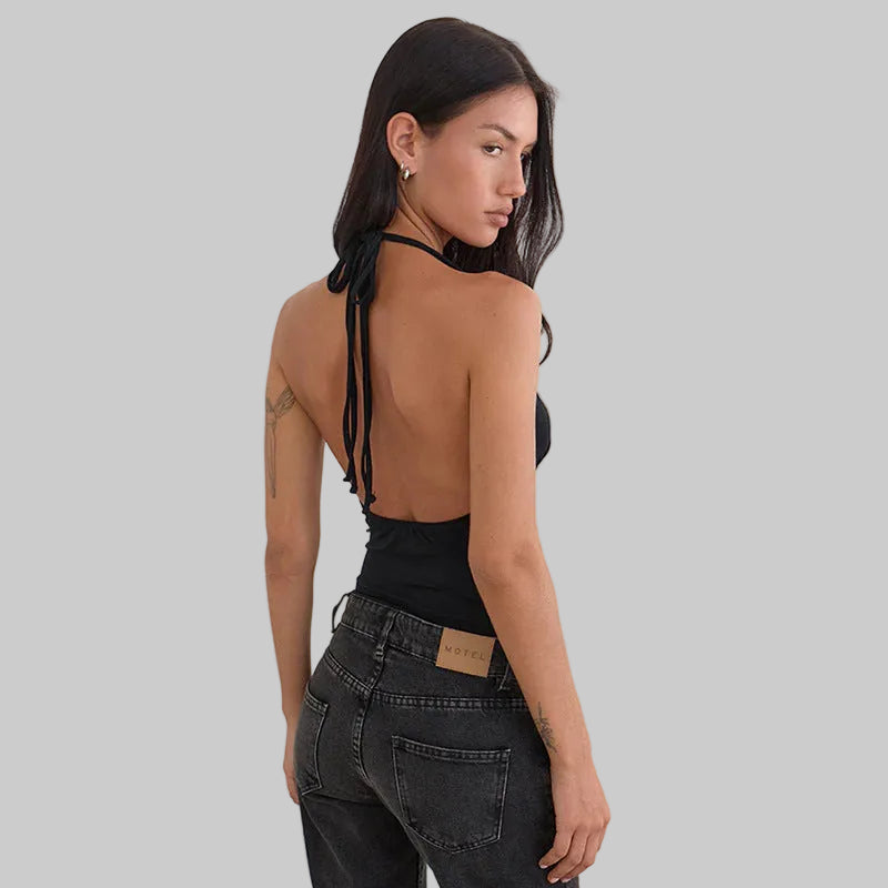 Woman wearing a black halter top and dark jeans on a white background