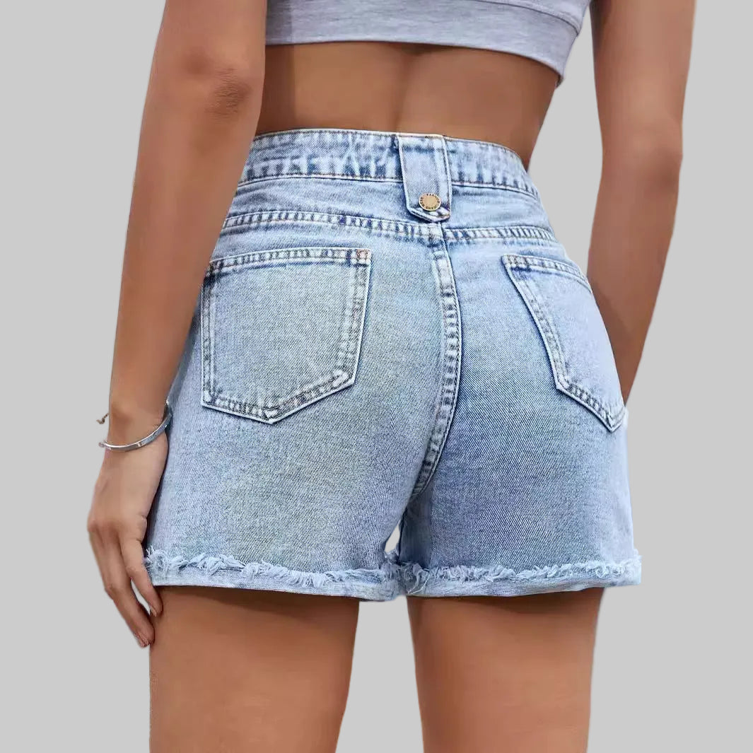 Person wearing light blue denim shorts with a blurred background