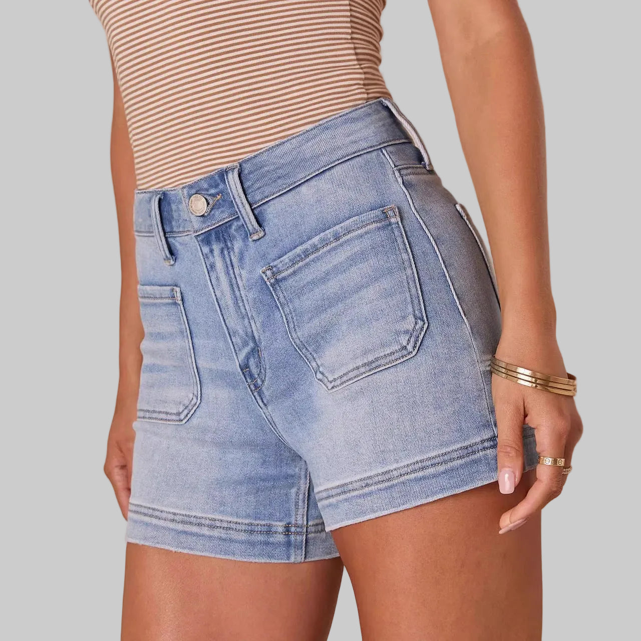 Person wearing light blue denim shorts on a beige background